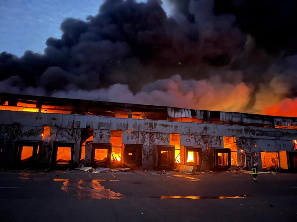 A warehouse storing frozen products is seen on fire after shelling, as Russia's attack on Ukraine continues, in the village of Kvitneve in Kyiv region, Ukraine, in this handout picture released March 12, 2022. Press service of the State Emergency Service of Ukraine/Handout via Reuters 
