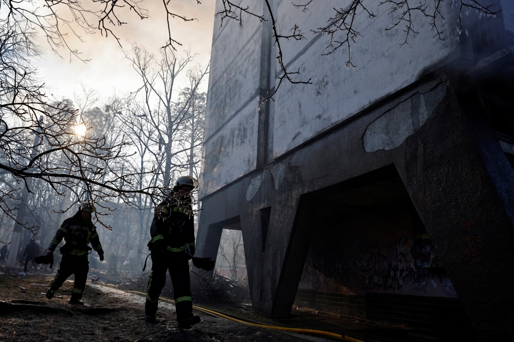 Firefighters walk as they help to put out a fire in a residential apartment building after it was hit by shelling as Russia's invasion of Ukraine continues, in Kyiv, Ukraine, March 15, 2022. REUTERS/Thomas Peter