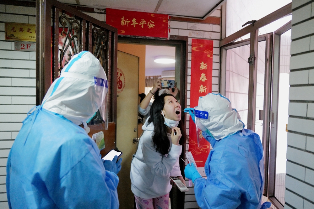 A worker in a protective suit collects a swab from a resident at a residential compound under lockdown, following the coronavirus disease (COVID-19) outbreak in Shenzhen, Guangdong province, China March 14, 2022. Picture taken March 14, 2022. cnsphoto via REUTERS