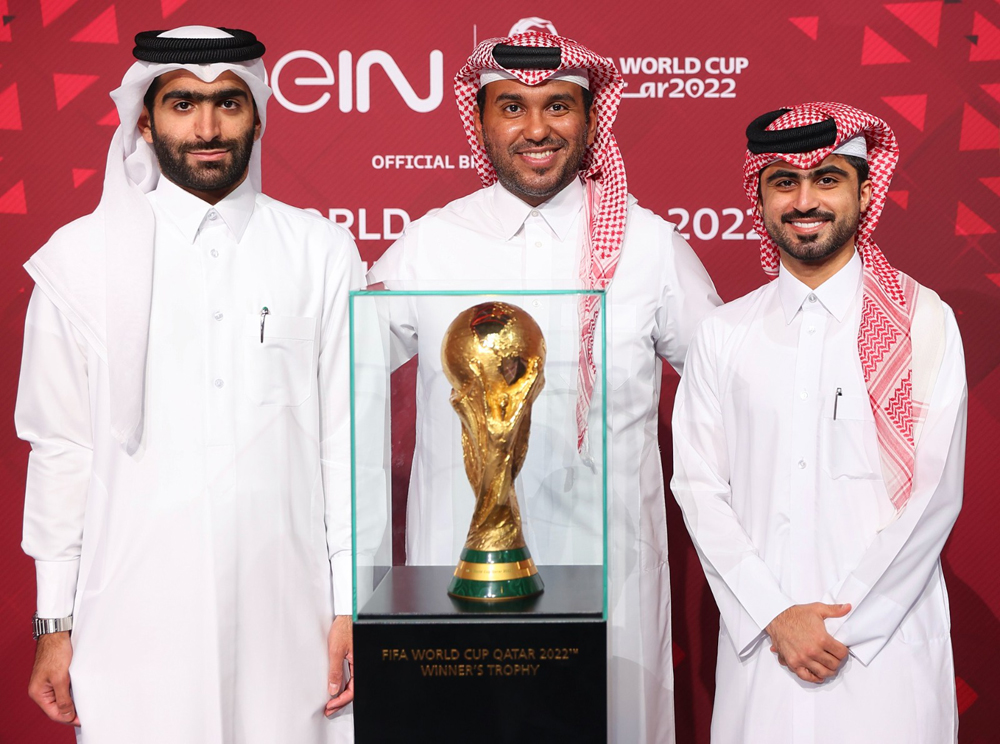 beIN Media Group employees pose for a photograph with the FIFA World Cup trophy.