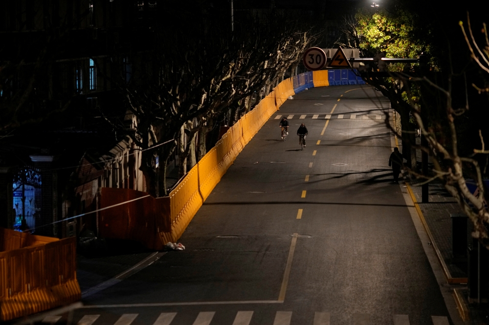 People pass by barriers that have been built to separate residential buildings from a street, amid the coronavirus disease (COVID-19) pandemic, in Shanghai, China March 22, 2022. REUTERS/Aly Song