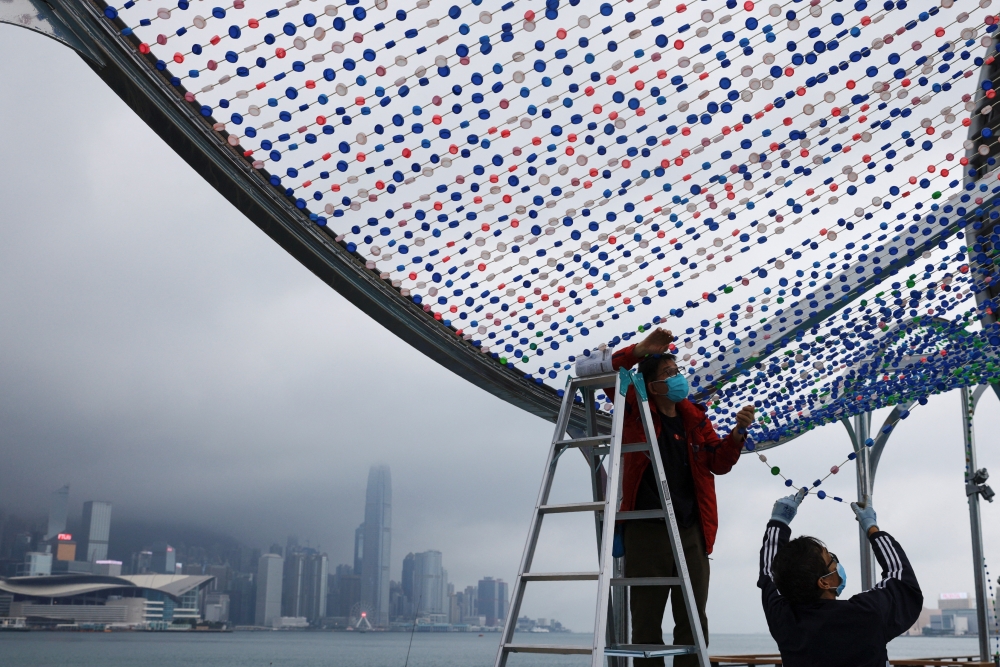 People wearing face masks work next to Victoria Harbour, amid the coronavirus disease (COVID-19) pandemic, in Hong Kong, China, March 25, 2022. REUTERS/Tyrone Siu