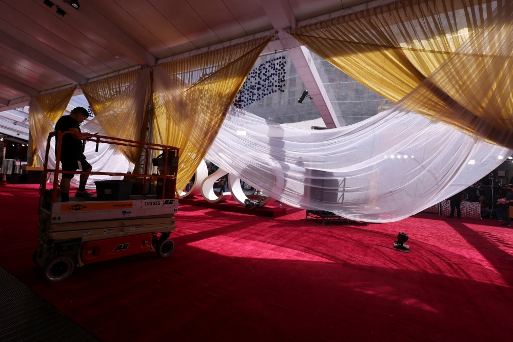 A worker puts the last minute touches on the red carpet arrivals area as preparations continue in Hollywood for the Academy Awards in Los Angeles, California, U.S., March 26, 2022. REUTERS/Mike Blake