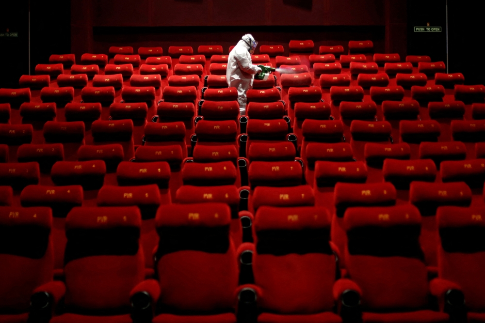 A worker wearing protective gear sprays disinfectant inside an empty PVR multiplex that was closed following the outbreak of the coronavirus disease (COVID-19), in New Delhi, India July 31, 2020. REUTERS/Adnan Abidi/File Photo