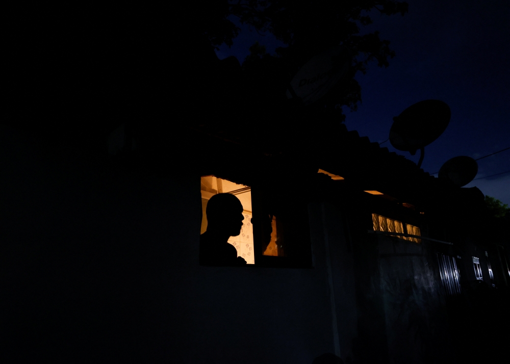 A man looks out from a window while talking to a person during the power cut in Colombo, Sri Lanka March 30, 2022. Reuters/Dinuka Liyanawatte