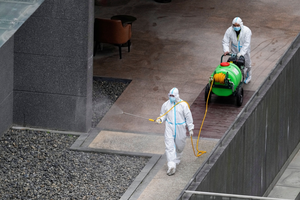 Workers in protective suit spray disinfectant at a community, during the lockdown to curb the spread of the coronavirus disease (COVID-19) in Shanghai, China, April 5, 2022. Reuters/Aly Song
 