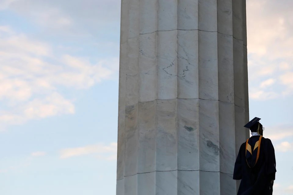 A person in graduation regalia stands on the Lincoln Memorial in Washington, D.C., U.S., May 14, 2021. REUTERS/Andrew Kelly/File Photo

