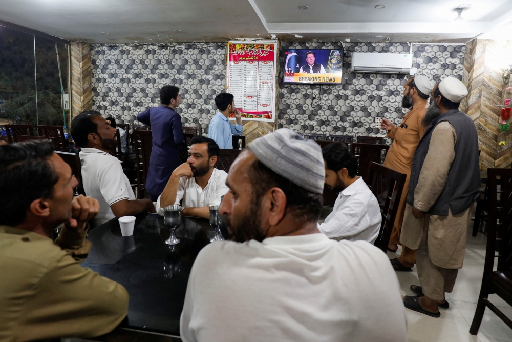 People watch the speech of Pakistani Prime Minister Imran Khan on a television screen, at a cafe in Islamabad, Pakistan, April 8, 2022. (Reuters/Akhtar Soomro)