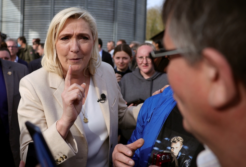 Marine Le Pen, French far-right National Rally (Rassemblement National) party candidate for the 2022 French presidential election, talks with a supporter, in Soucy, France, April 11, 2022. Reuters/Sarah Meyssonnier