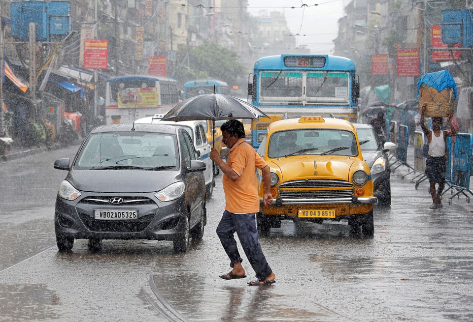 A man carrying an umbrella runs as he crosses a busy road during rain in Kolkata, India, July 10, 2018. REUTERS/Rupak De Chowdhuri


