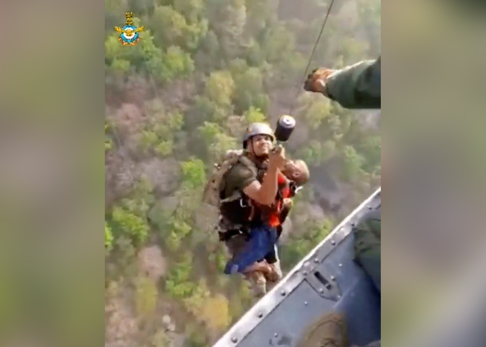 A rescuer carries a child to a helicopter during a rescue operation after mid-air collision of two cable cars on Sunday trapped nearly 50 people in a dozen cars, in Deoghar district, Jharkhand state, India in this still image taken from a handout video obtained April 12, 2022. Courtesy Indian Air Force/Handout via REUTERS