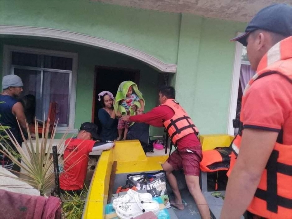 A rescuer assists a woman and a child onto a rescue boat, after the tropical storm Megi hit, in Capiz, Philippines April 12, 2022. Philippine Coast Guard/Handout via Reuters