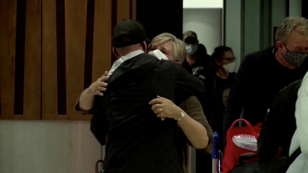 People hug in the arrivals area at the Auckland Airport, as Australians started arriving after the country opened its borders to travellers from its neighbouring nation for the first time since mid-2021, in Auckland, New Zealand, April 13, 2022 in this still image taken from a video. TVNZ/Handout via REUTERS
