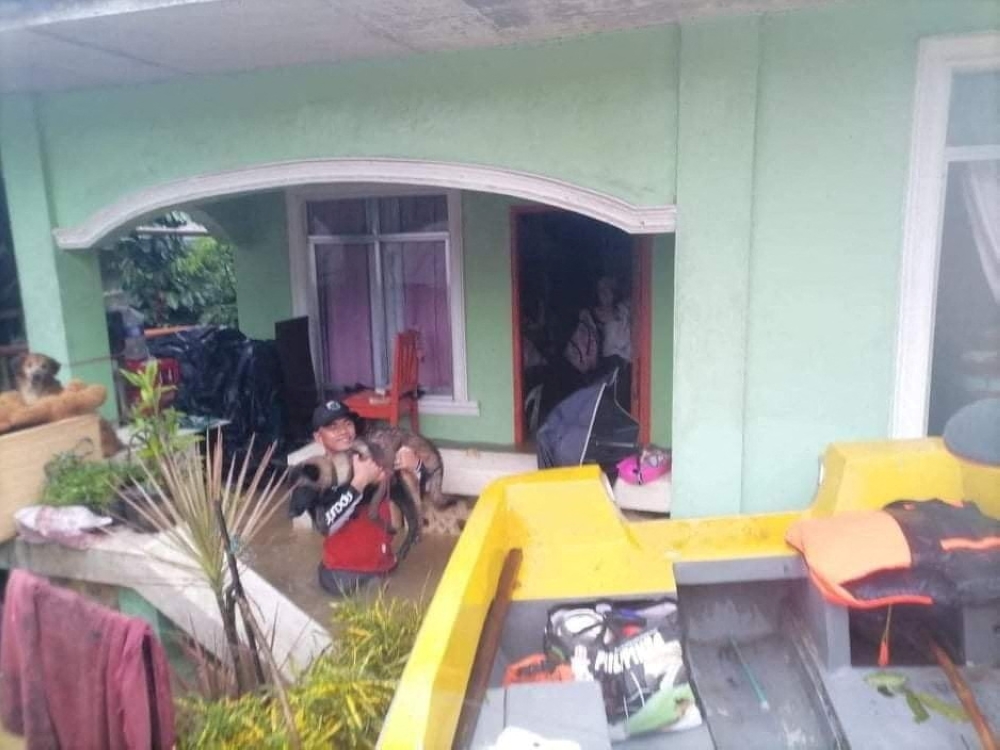 A rescuer carries a dog amidst flooding, after the tropical storm Megi hit, in Capiz, Philippines April 12, 2022. Picture taken April 12, 2022. Philippine Coast Guard/Handout via Reuters