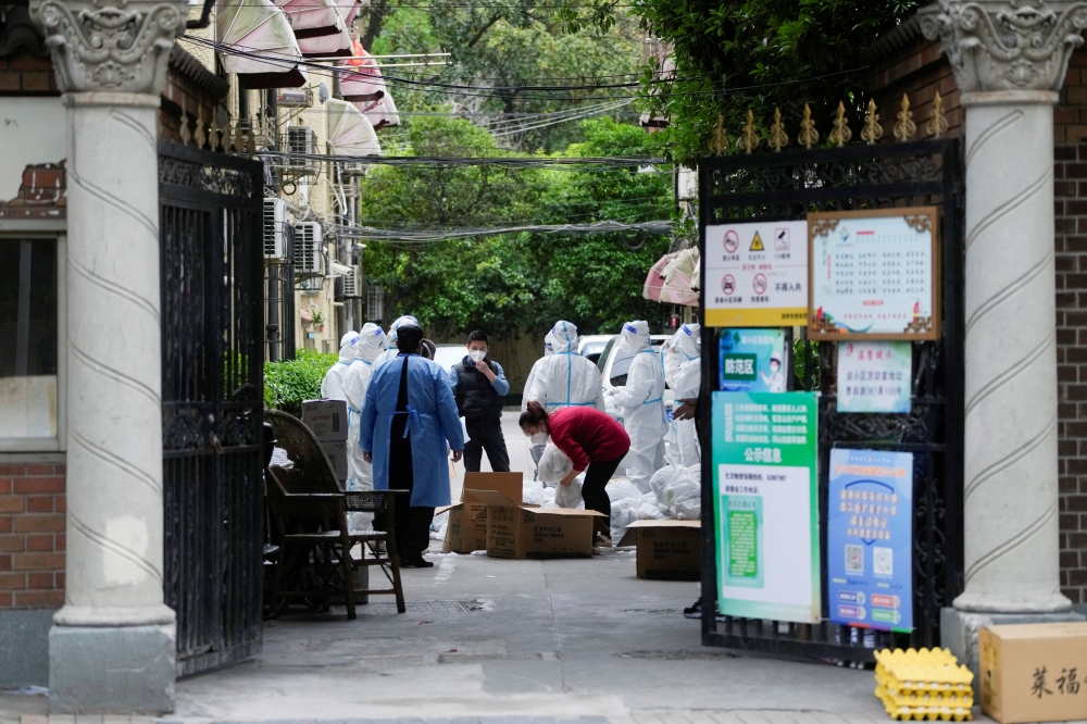 Workers in protective suits are seen at a residential area under lockdown amid the coronavirus disease (COVID-19) pandemic, in Shanghai, China April 15, 2022. REUTERS/Aly Song