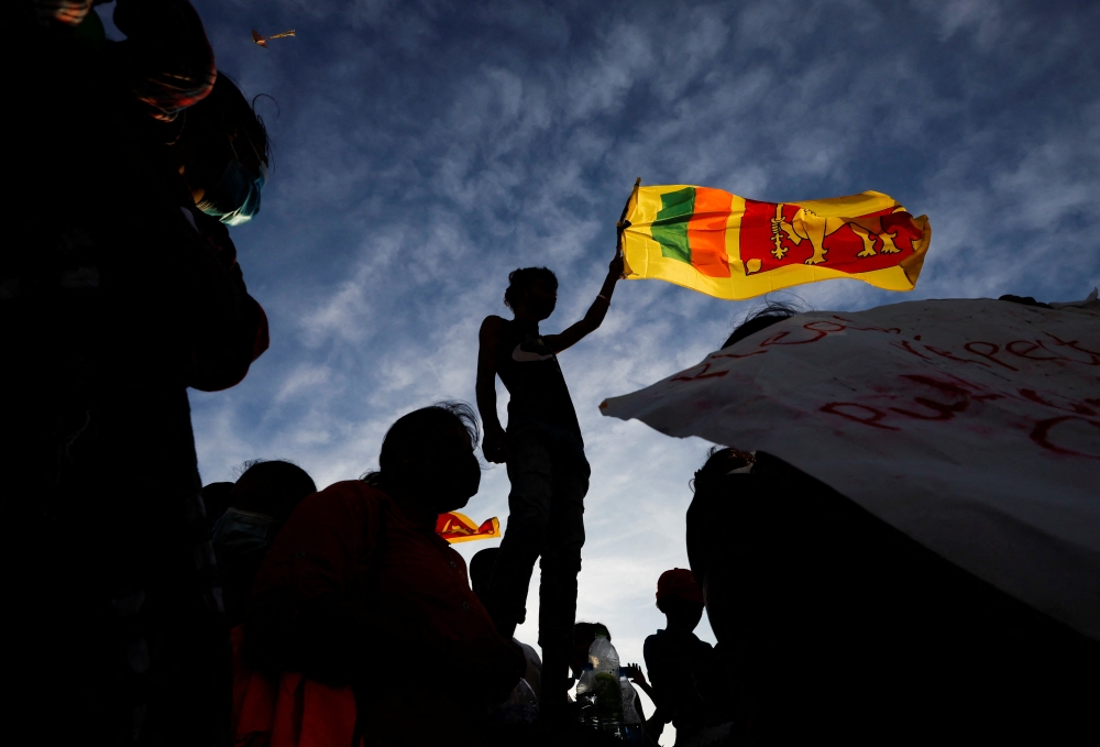 A demonstrator holding the Sri Lankan national flag is silhouetted during the protest against Sri Lankan President Gotabaya Rajapaksa, in Colombo, Sri Lanka, April 15, 2022. Reuters/Navesh Chitrakar

