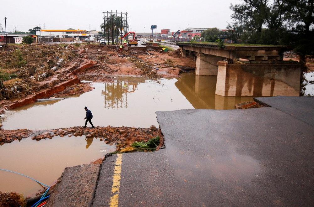 A man walks around a damaged bridge caused by flooding in Umlazi near Durban, South Africa, April 16, 2022. REUTERS/Rogan Ward/File Photo

