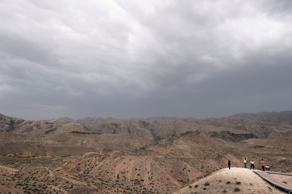 Tourists stand on a hill overlooking an arid terrain in the south of Ningxia Hui Autonomous Region, China July 27, 2021. Picture taken July 27, 2021. REUTERS/Ryan Woo