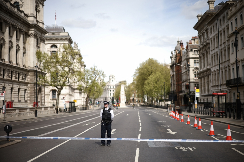 A police officer stands at a cordon on Whitehall in Westminster after the road was closed following an incident involving the arrest of a man near Downing Street, in London, Britain, April 18, 2022. REUTERS/Henry Nicholls