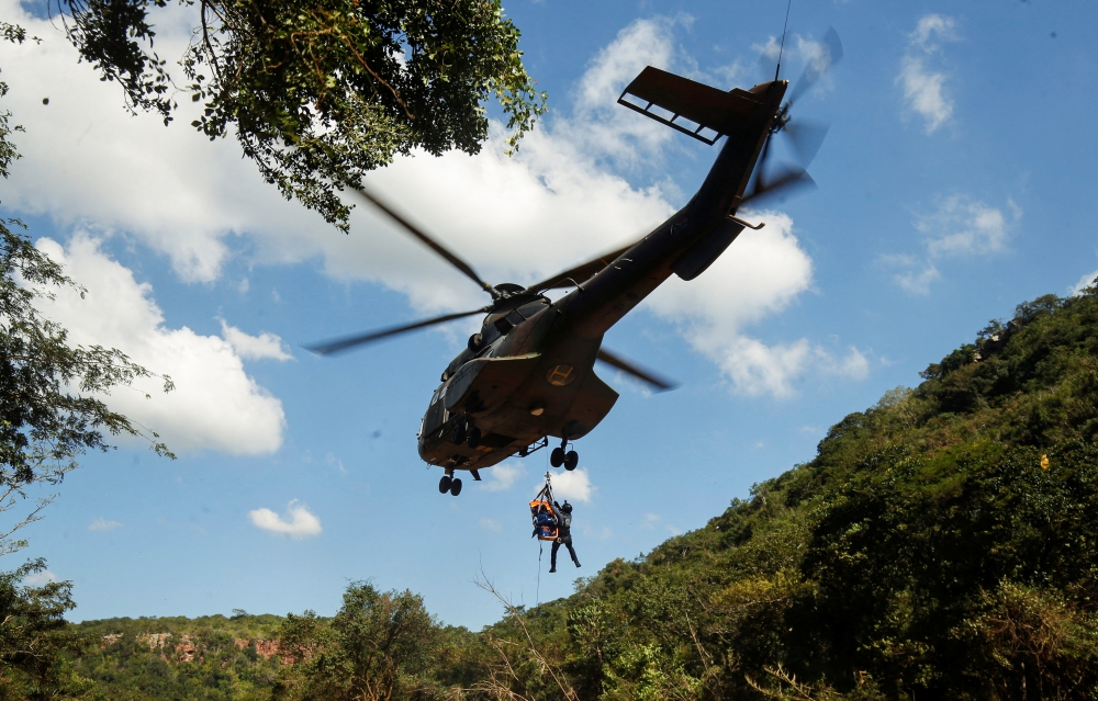 A member of a search and rescue team airlifts a body from the Mzinyathi River after heavy rains caused flooding near Durban, South Africa, April 19, 2022. REUTERS/Rogan Ward