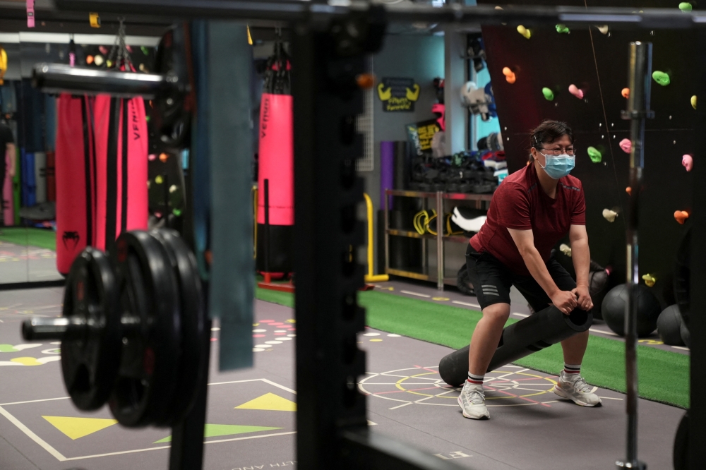 A woman wearing a face mask exercises at a gym on the day of its reopening following the coronavirus disease (COVID-19) outbreak, in Hong Kong, China, April 21, 2022. REUTERS/Lam Yik