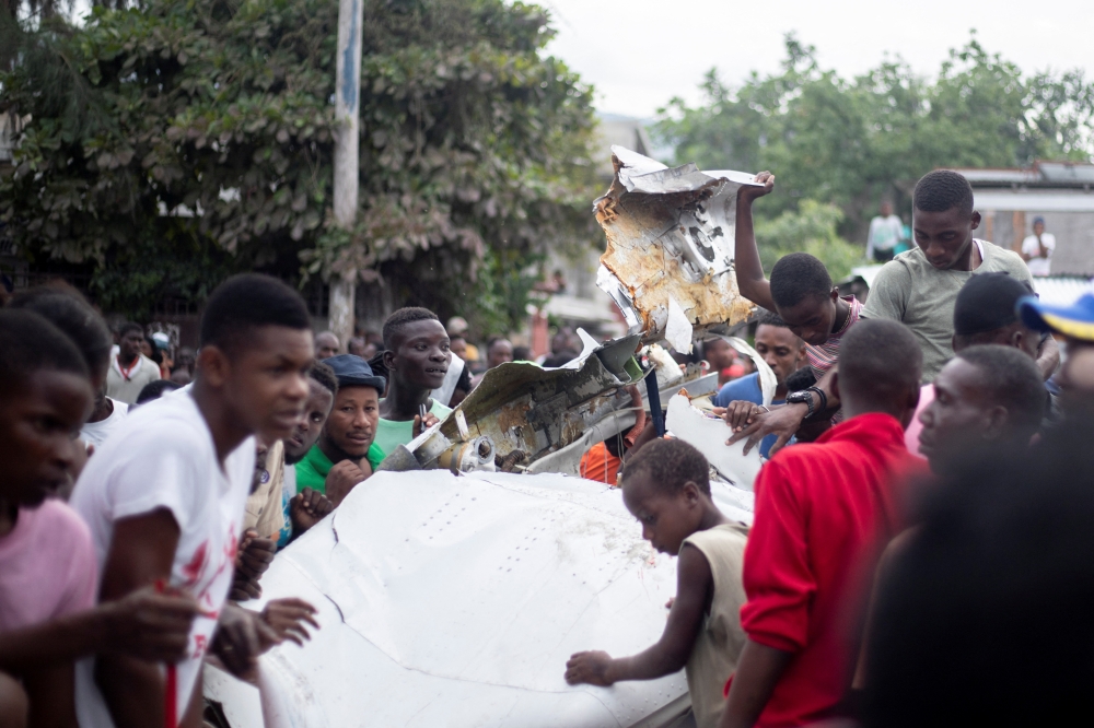 People gather around the wreckage of a small plane that crashed onto a busy street, killing multiple people including the pilot, in Port-au-Prince, Haiti, April 20, 2022. Picture taken April 20, 2022. REUTERS/Lutherson Leon
