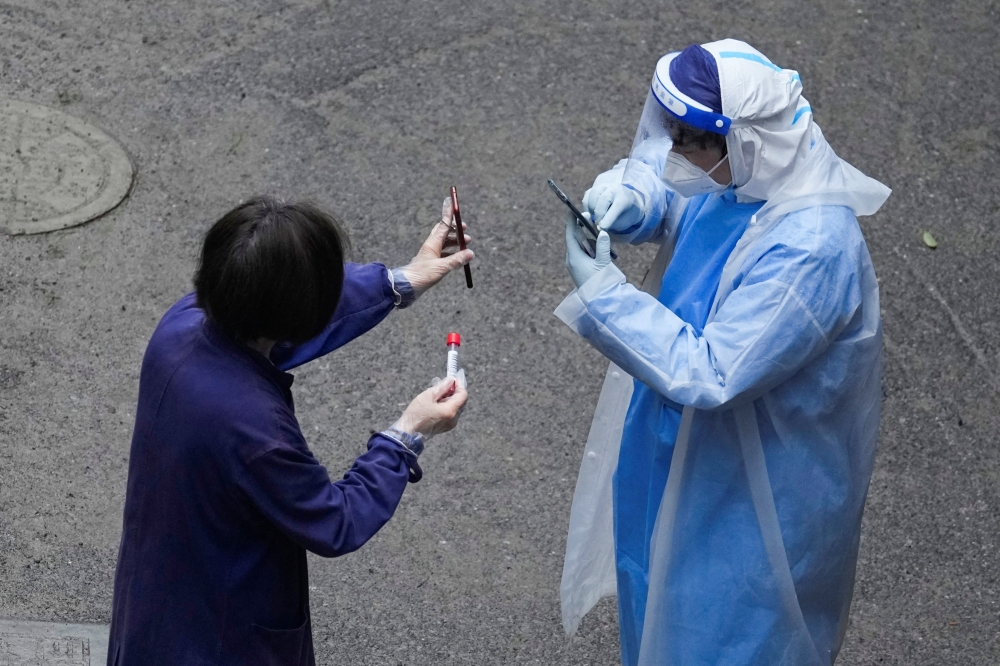 A worker in a protective suit checks QR code on the phone of a resident for nucleic acid testing during lockdown, amid the coronavirus disease (COVID-19) pandemic, in Shanghai, China, April 26, 2022. Reuters/Aly Song