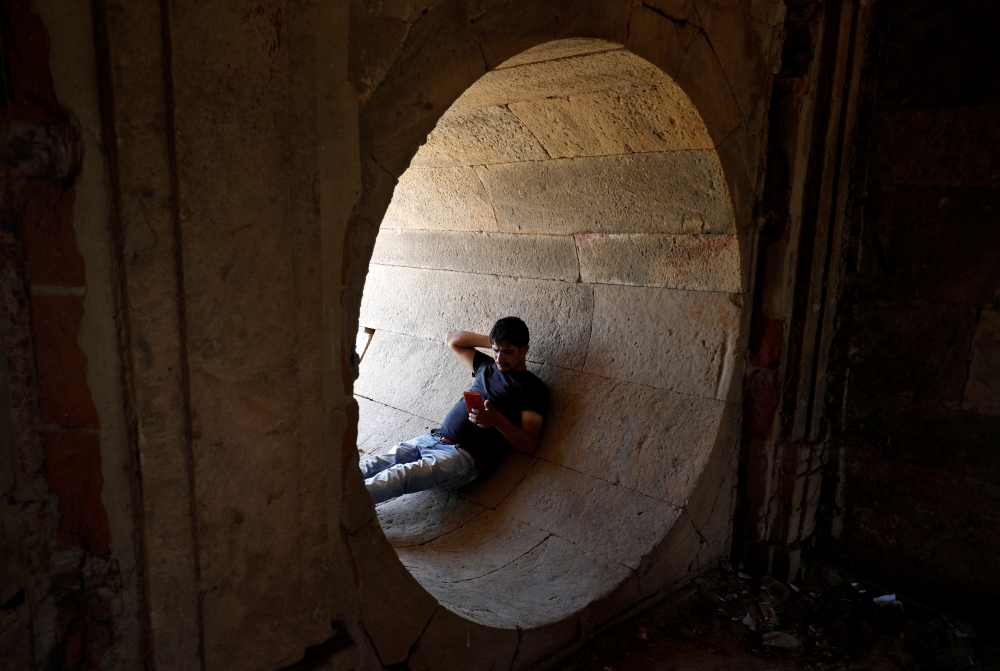 A man rests in a dry water tunnel of the Sarkhej Roza lake during hot weather in Ahmedabad, India, April 28, 2022. REUTERS/Amit Dave