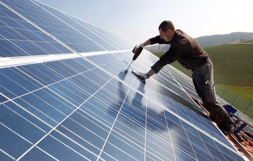 A worker mounts 320 square metres of solar panels on the roof of a farmstead barn in Binsham near Landshut March 21, 2012./File Photo