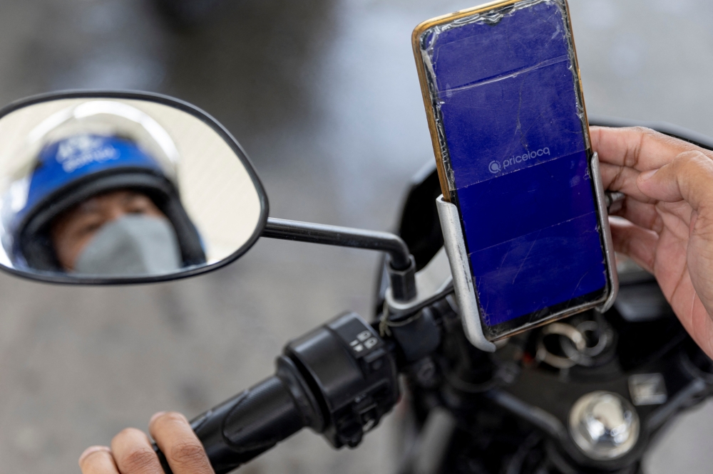A motorcycle rider uses the PriceLOCQ app to refuel in a gas station in Muntinlupa, Metro Manila, Philippines April 7, 2022. Picture taken April 7, 2022. REUTERS/Eloisa Lopez