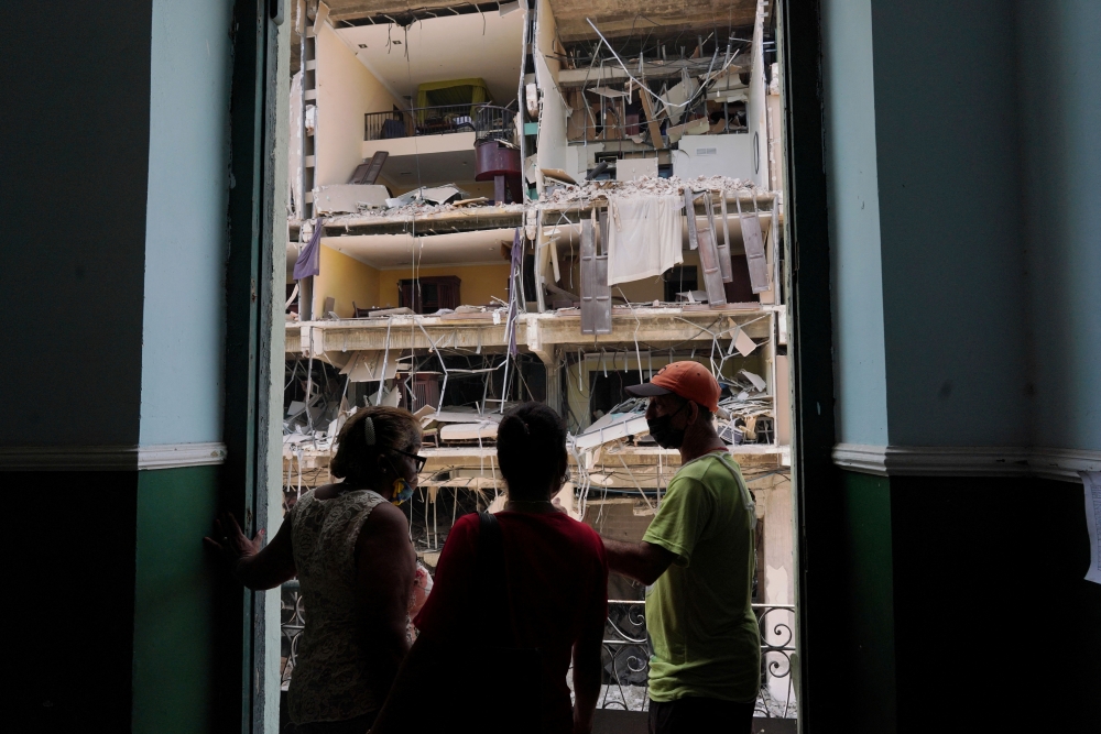 Workers chat at the balcony of a school beside the Saratoga Hotel a day after it suffered an explosion, in Havana, Cuba May 7, 2022. REUTERS/Alexandre Meneghini