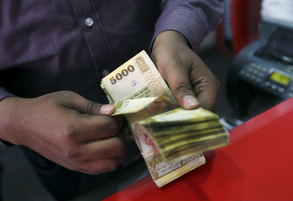A man counts Sri Lankan rupees at a money exchange counter in Colombo September 4, 2015. REUTERS/Dinuka Liyanawatte

