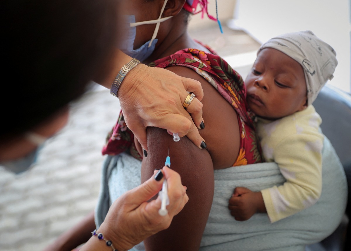 FILE PHOTO: A healthcare worker administers the coronavirus disease (COVID-19) vaccine to a woman, amidst spread of the SARS-CoV-2 variant Omicron in Johannesburg, South Africa, December 04, 2021. Picture taken December 04, 2021. REUTERS/Sumaya Hisham/File Photo
