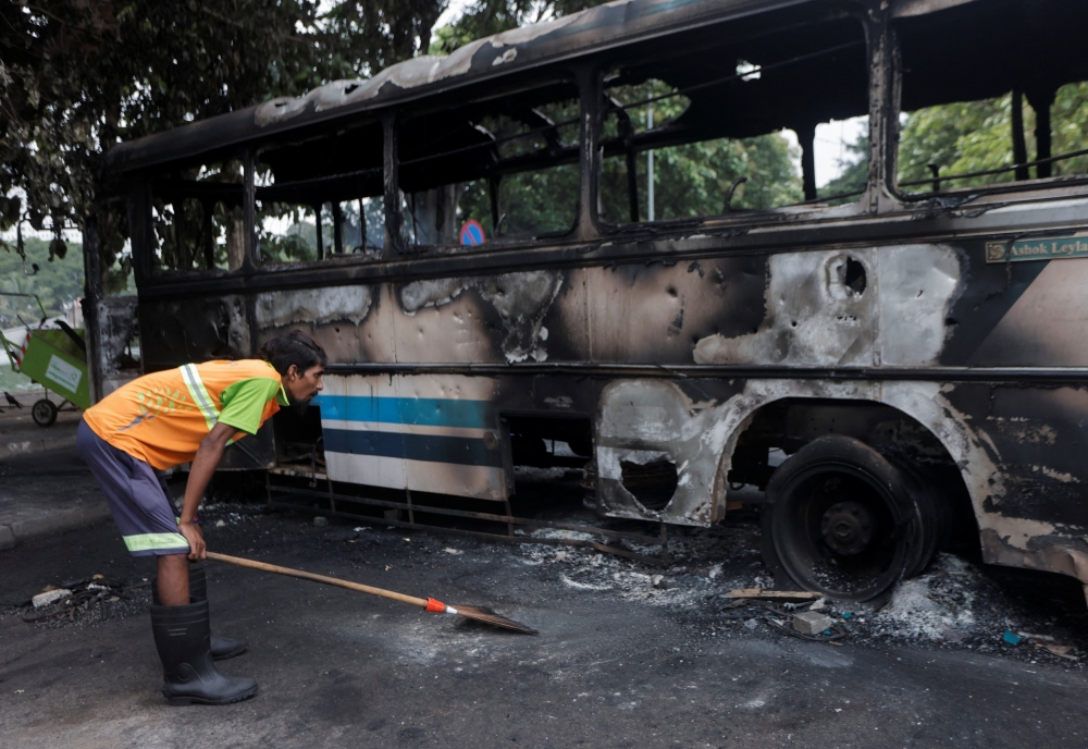 A man looks at a damaged bus of Sri Lanka's ruling party supporters after it was set on fire during a clash of pro and anti-government demonstrators near the Prime Minister's official residence, amid the country's economic crisis, in Colombo, Sri Lanka, May 10, 2022. REUTERS