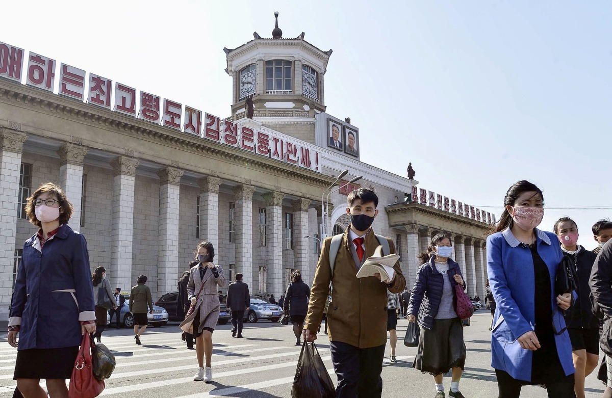 FILE PHOTO: People wearing protective face masks walk amid concerns over the new coronavirus disease (COVID-19) in front of Pyongyang Station in Pyongyang, North Korea April 27, 2020, in this photo released by Kyodo. Mandatory credit Kyodo/via REUTERS 