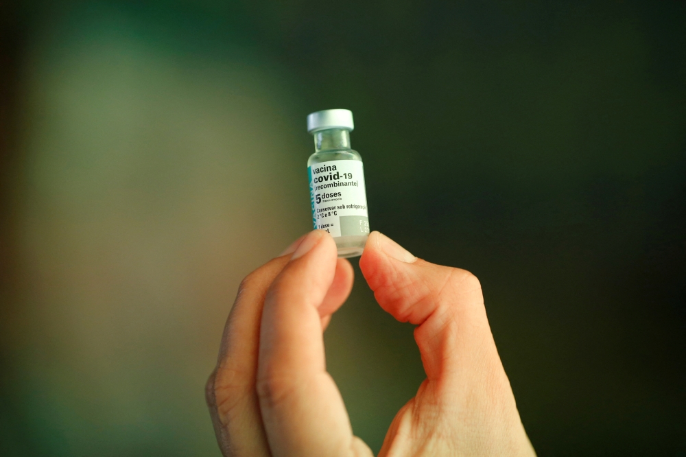 A healthcare worker holds a vial of the AstraZeneca vaccine during a ceremony to announce the AstraZeneca vaccine being produced in the country by Fiocruz Institute, in Brasilia, Brazil February 22, 2022. REUTERS/Adriano Machado/File Photo