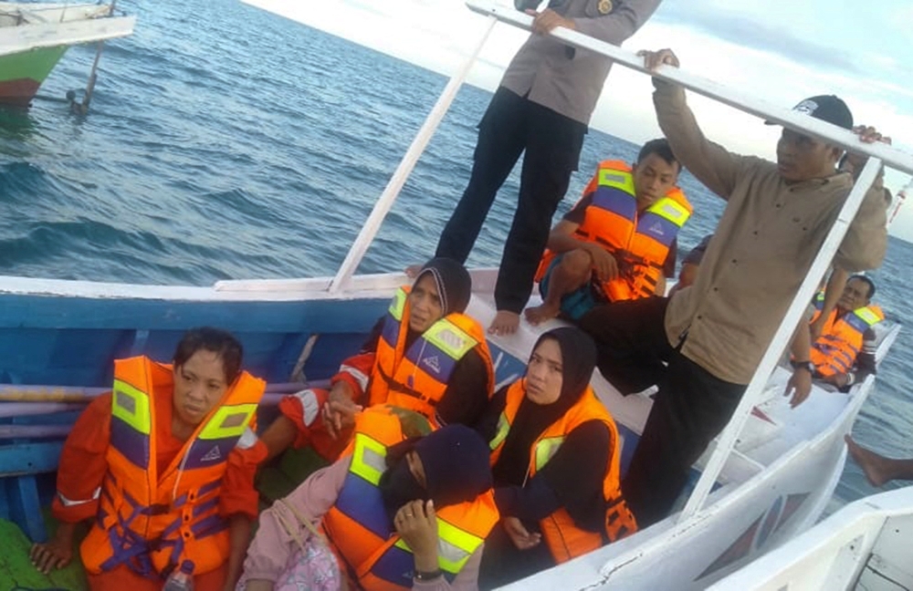 Survivors sit on wooden boat while being rescued, after a boat with 43 people on board capsized off Sulawesi island in Takalar regency, South Sulawesi province, Indonesia. Antara Foto/National Search and Rescue Agency/ via Reuters