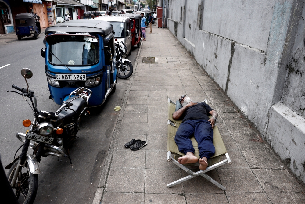 A man sleeps on a folding bed on a pavement as he waits in queue to buy petrol due to fuel shortage, amid the country's economic crisis, in Colombo, Sri Lanka on June 17, 2022. (REUTERS/Dinuka Liyanawatte/FILE PHOTO)