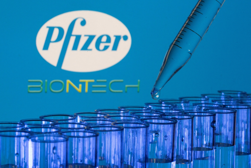 FILE PHOTO: Test tubes are seen in front of displayed Pfizer and Biontech logos in this illustration taken, May 21, 2021. REUTERS/Dado Ruvic/Illustration