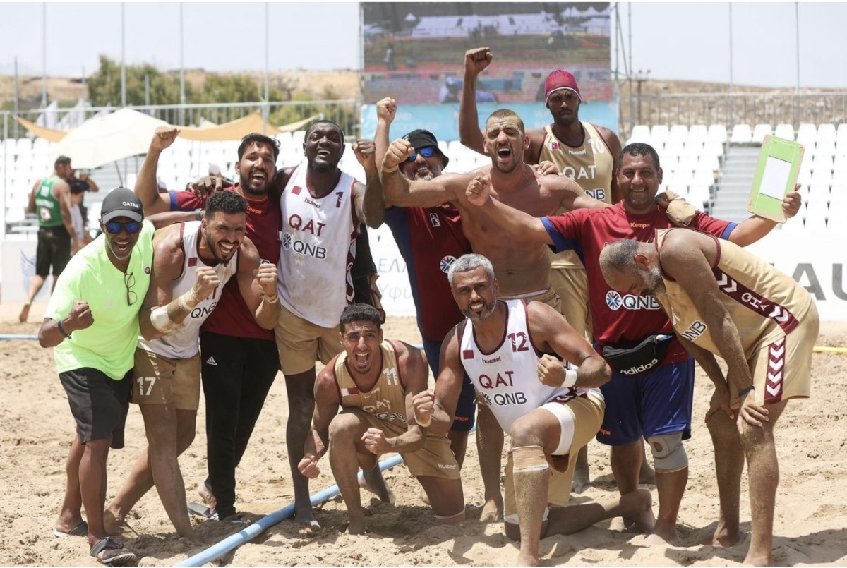 Qatar players and officials celebrate after winning a match during the IHF Beach Handball World Championships in Greece.