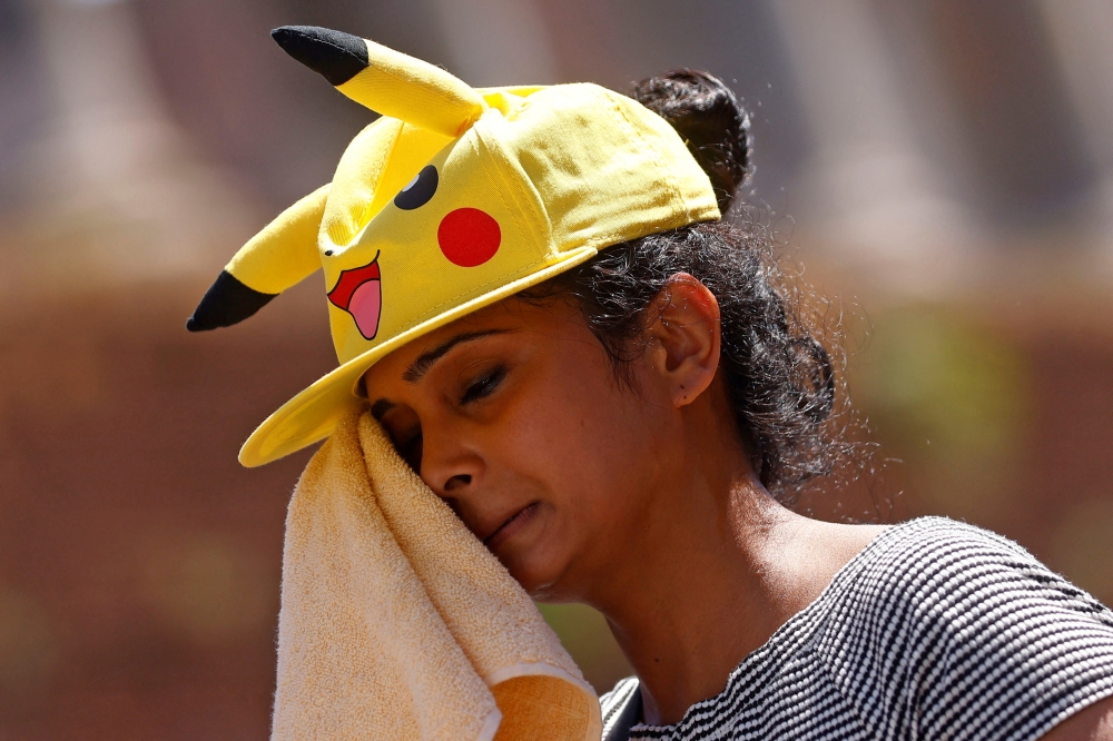 A woman wipes off sweat with a towel near the Colosseum during a heatwave across Italy, in Rome, August 12, 2021. REUTERS/Guglielmo Mangiapane/File Photo

