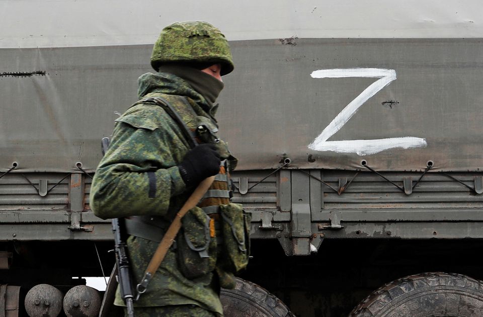 A serviceman of pro-Russian militia walks nest to a military convoy of armed forces of the separatist self-proclaimed Luhansk People's Republic (LNR) on a road in the Luhansk region, Ukraine February 27, 2022. REUTERS/Alexander Ermochenko
