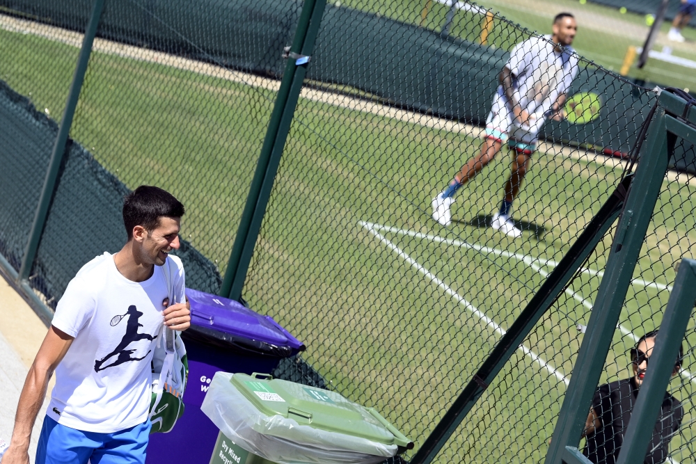 Australia's Nick Kyrgios during training as Serbia's Novak Djokovic walks past after his training. (REUTERS/Toby Melville)