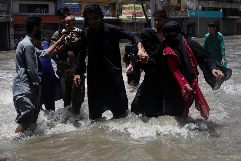 A family wades through a flooded street during the monsoon season, in Karachi, Pakistan, on July 11, 2022. (REUTERS/Akhtar Soomro)

