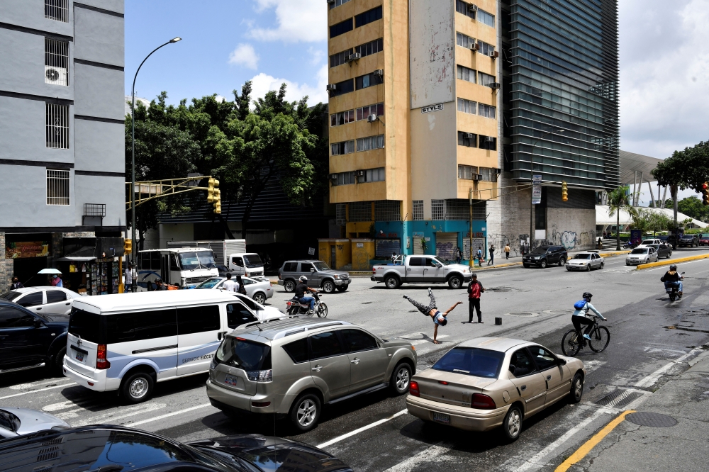 Venezuelan professional breakdance athlete Kenyer Mendez, 27, who has gone viral by performing a head slide trick to make a living dancing at Colombia's traffic lights and dreams of joining Venezuela's first Olympic breakdance team in 2024, performs at a traffic light, in Caracas, Venezuela, recently. (REUTERS/Gaby Oraa)