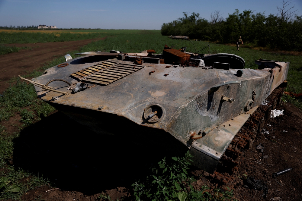 A Ukrainian soldier walks past destroyed Russian tanks in a field, in Mykolaiv region, Ukraine, on June 12, 2022. (REUTERS/Edgar Su)