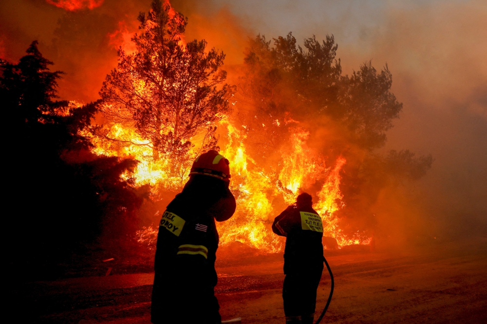 Firefighters try to extinguish a wildfire in Ntrafi, Athens, Greece, July 19, 2022. (REUTERS/Costas Baltas)