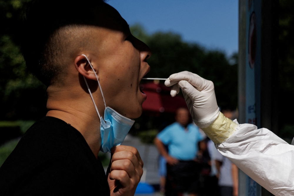 A man gets a swab test at a nucleic acid testing station, following a coronavirus disease (COVID-19) outbreak, in Beijing, China, July 14, 2022. REUTERS/Thomas Peter/File Photo