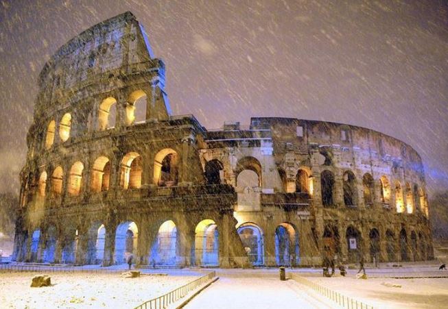 The ancient Colosseum is seen during heavy snowfalls late at night in Rome on February 4, 2012. (REUTERS/Gabriele Forzano)