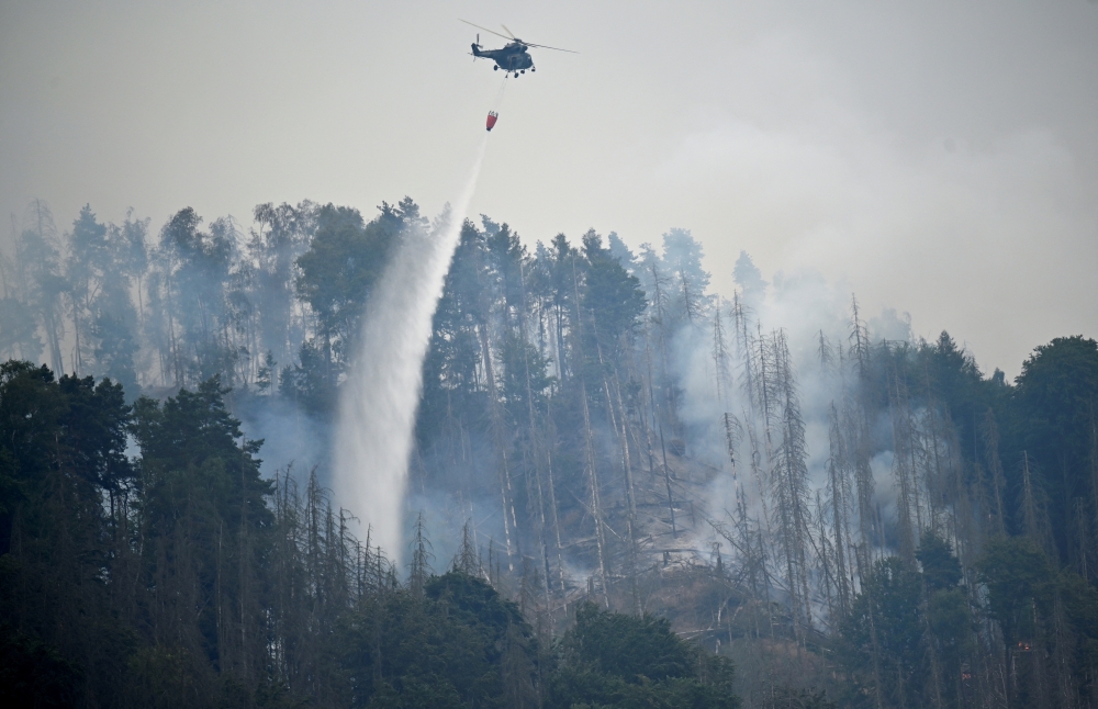 A Czech army helicopter helps to extinguish a forest fire, during a heatwave, close to the German-Czech border near Schmilka, Germany, July 26, 2022. REUTERS/Matthias Rietschel